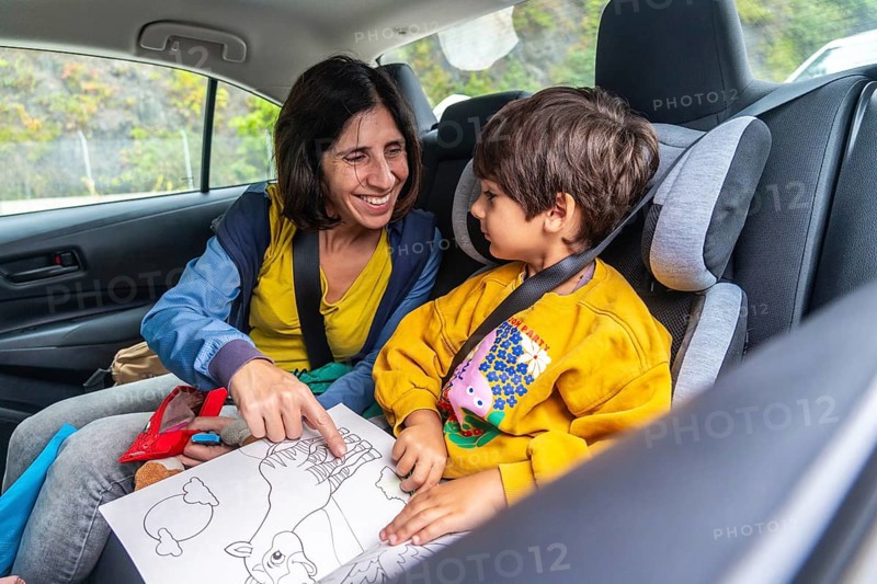 Mother and son sharing joyful moments during a road trip, reading a colorful children's book together and creating cherished memories that will last a lifetime