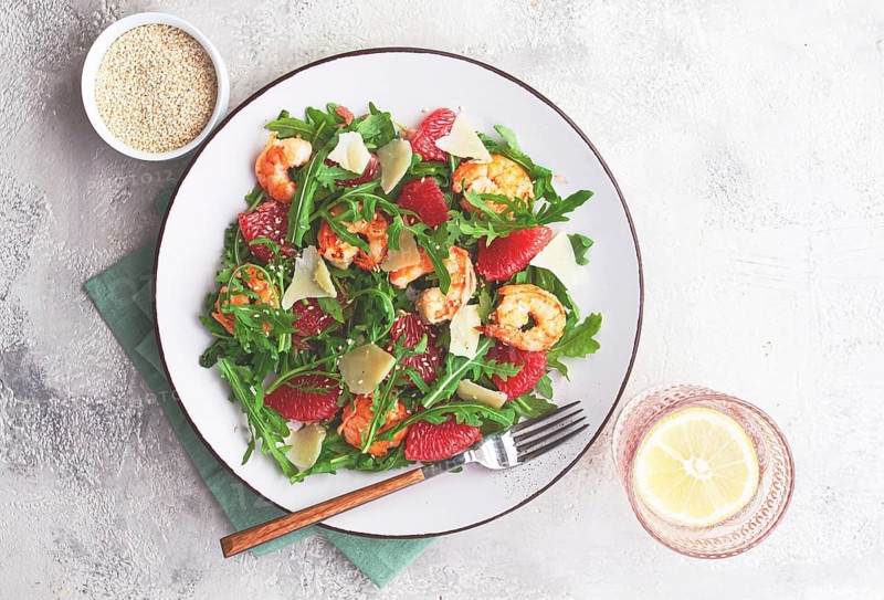 Fresh shrimp salad with arugula, grapefruit, and parmesan served in a bowl