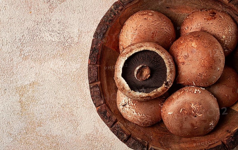 Fresh Portobello mushrooms, in a wooden bowl, top view, close-up, no people
