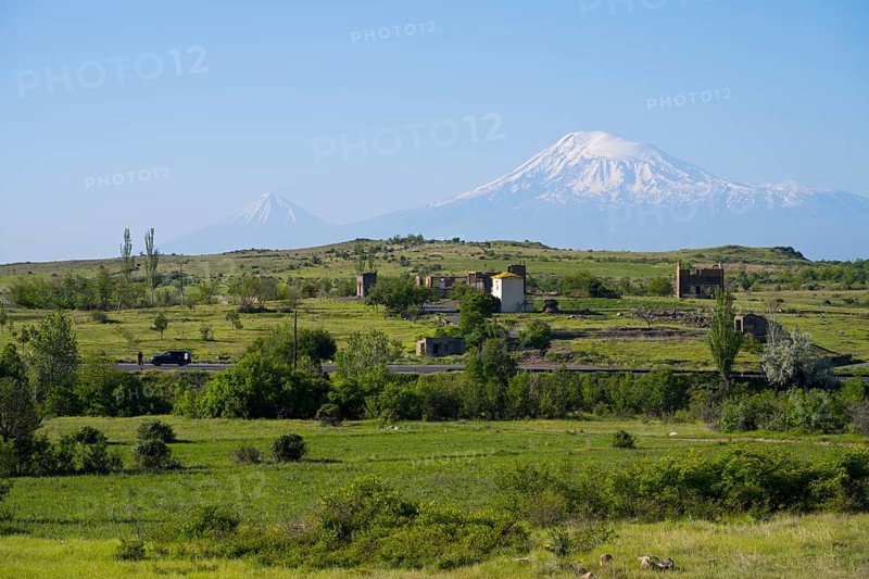 Wide green landscape with views of snow-capped mountains and scattered huts, view of large and small Ararat in Turkey, near Ujan, Aragazotn province, Armenia, AsiaArmenia, Asia