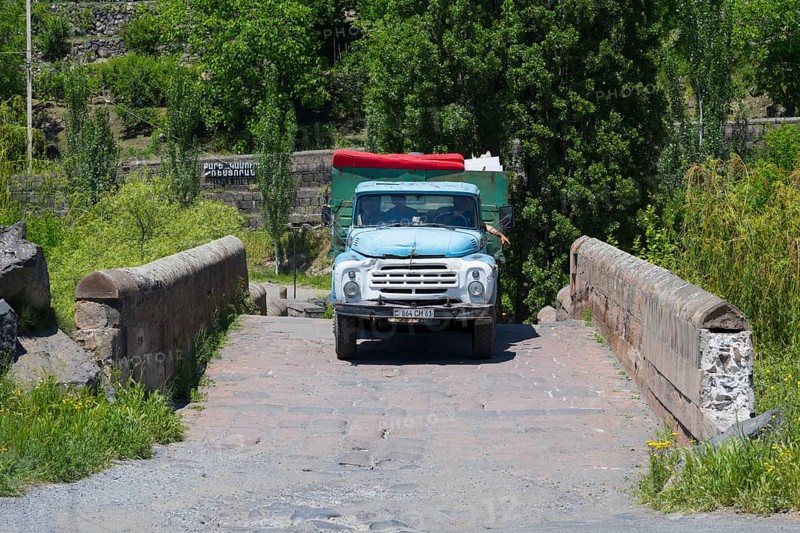 A blue truck drives over an old stone bridge surrounded by trees, truck ZIL-130 drives over Kassagh bridge from 1664, Ashtarak bridge, Ashtarak, Aštarak, Aragazotn province, Armenia