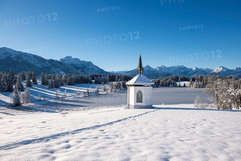 Idyllic chapel in snow with footprints in a picturesque winter landscape, Hegratsrieder See, near Füssen, Ostallgäu, Allgäu, Bavaria, Germany