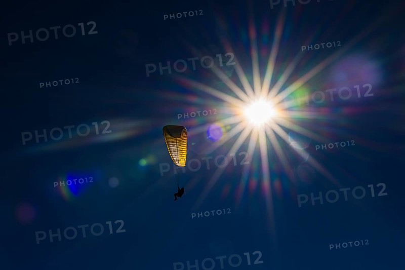 Paragliders against blue sky and bright sun, Val d'Anniviers, Valais Alps, Canton of Valais, Switzerland