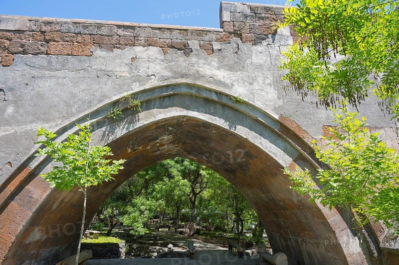 View of an old stone bridge structure against a wooded background on a sunny day, part of a three-arched bridge over the Kassagh from 1664, Ashtarak, Aštarak, Aragazotn province, Armenia