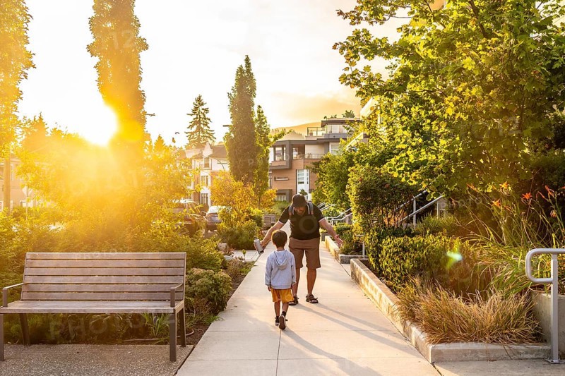 Father and son enjoying a leisurely stroll along a tree lined residential street in vancouver. British columbia. Bathed in the warm glow of the setting sun. Creating a peaceful and heartwarming scene