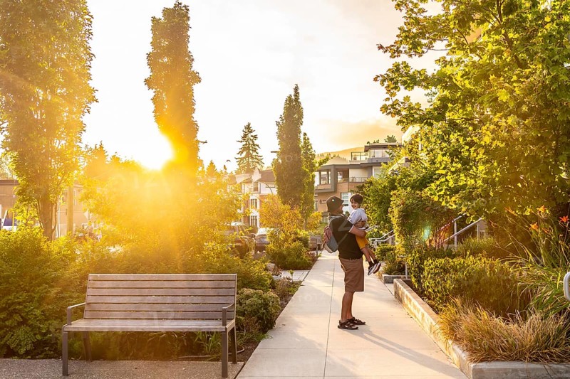 Father holding his son in a residential neighborhood of vancouver, british columbia, during a beautiful sunset, enjoying quality time together in a peaceful urban setting