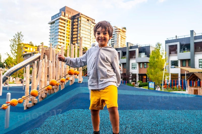 Smiling preschool child having fun in a colorful playground located in a residential area of vancouver, british columbia, promoting outdoor activities and urban childhood