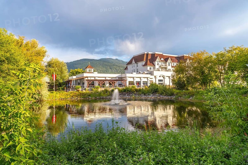 Picturesque salmon arm in british columbia features a luxurious hotel reflected in a serene pond, surrounded by lush greenery and majestic mountains