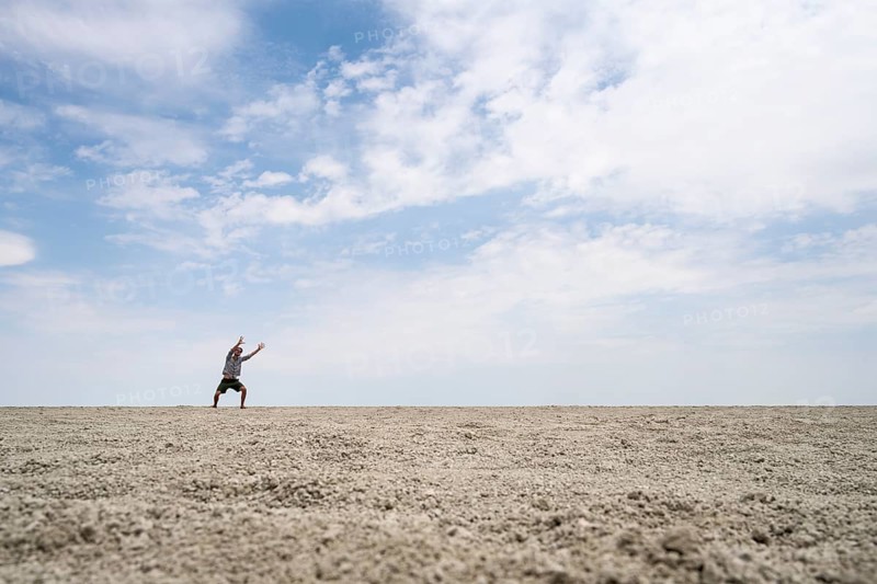 Symbolic picture, abstract, man raising his hands conjuring, on the Etosha pan, salt pan, Etosha National Park, Namibia