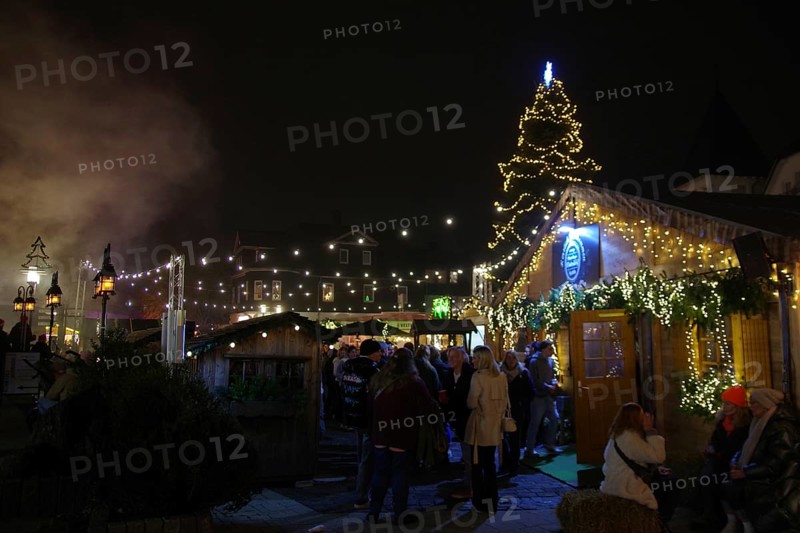 A lively Christmas market at night with illuminated wooden stalls and lots of visitors, Winterberg, North Rhine-Westphalia, Germany
