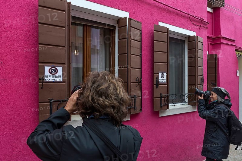 Tourists take pictures of a house in Burano, Venice, Italy