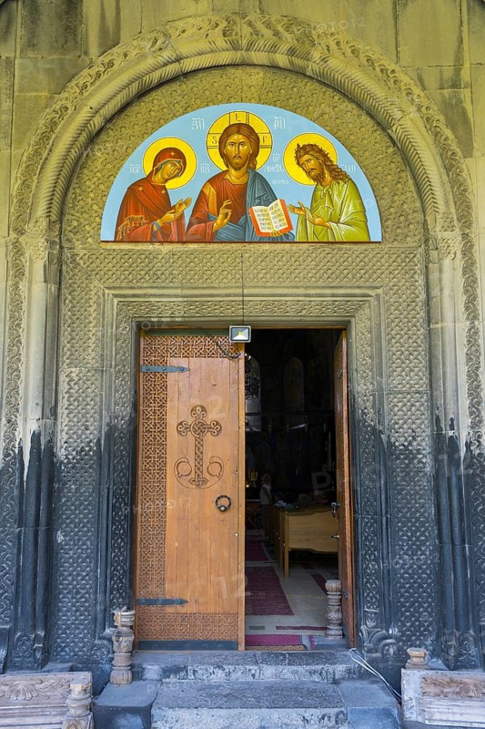 Opened wooden door with religious icon above, embedded in ancient stone decorated arch, Akhtala monastery, Akhtala, town of Akhtala, Lorikeet province, Armenia