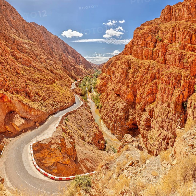 Serpentine road through steep, red rock walls under blue sky, Morocco, Dade Valley, panorama