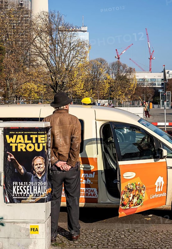 Taxi driver standing at curb waiting for passengers, Berlin, Germany