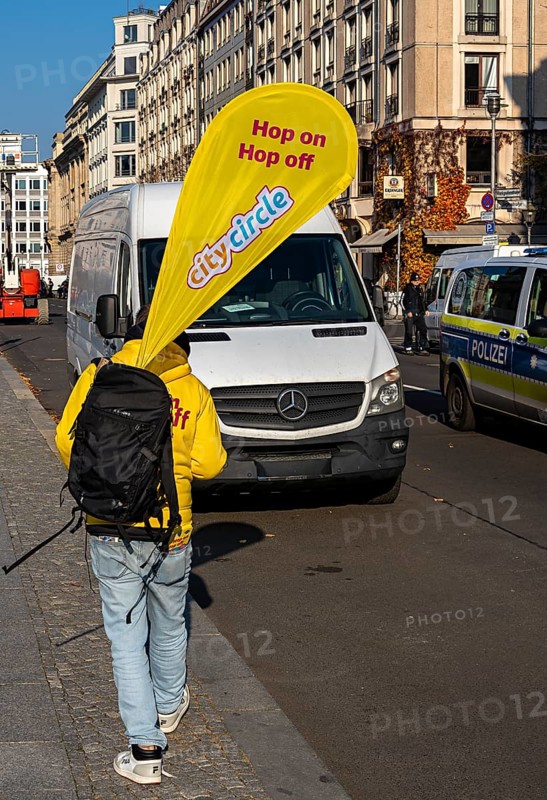 Cityscape, A man carrying the advertising banner of the Hop on Hop off buses from City Circle, Berlin, Germany