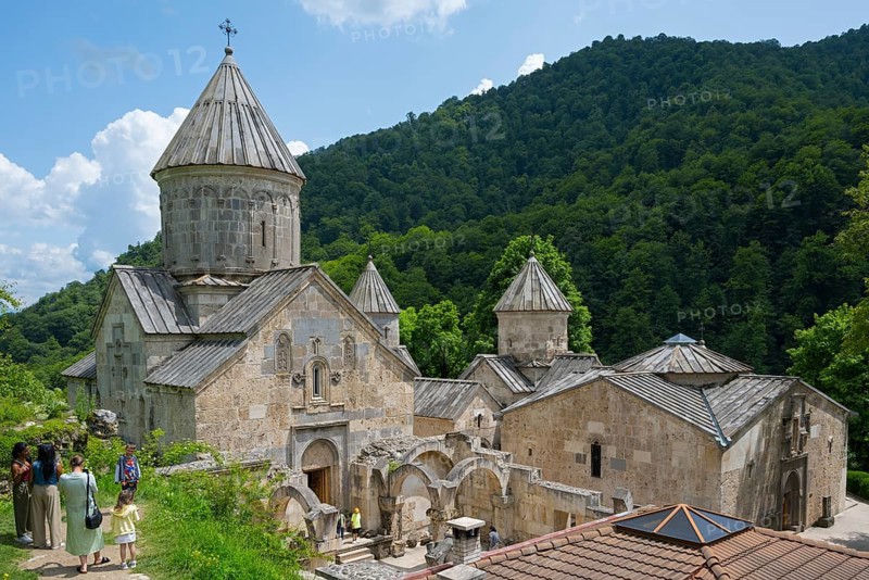 Monastery complex with towers and stone buildings against green mountains and sky background, Haghartsin Monastery, Hagarzin, Tavush Province, Armenia