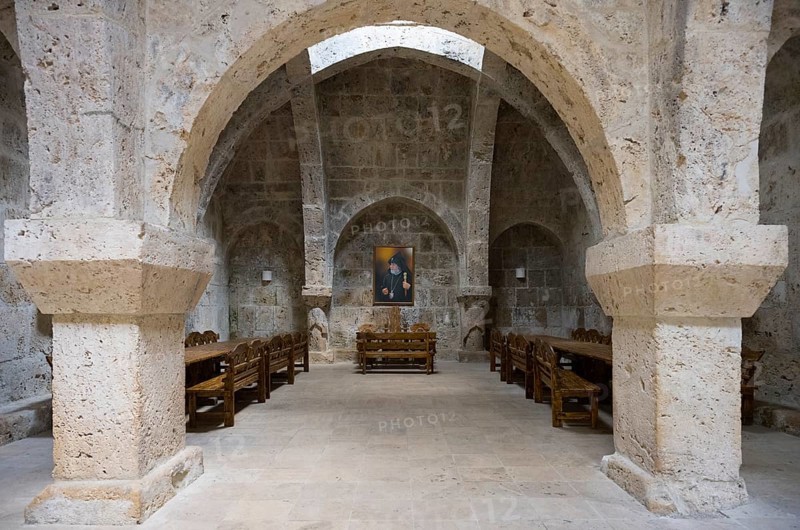 Stone vault with wooden furniture and paintings on the wall, sparse interior, refectory interior, dining room, Haghartsin monastery, Hagarzin, Tavush province, Armenia