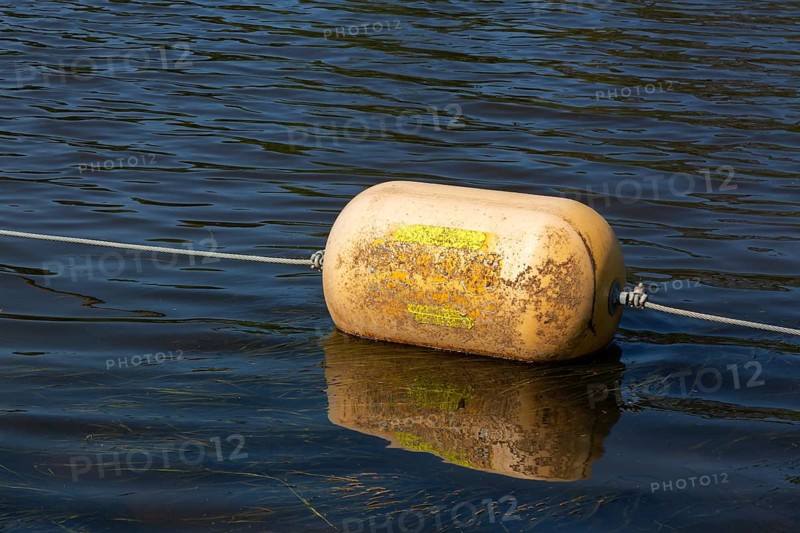 Yellow cautionary navigation buoy on river water surface serving to warn, signal or indicate of a hazard beyond, Terrebonne, Quebec, Canada