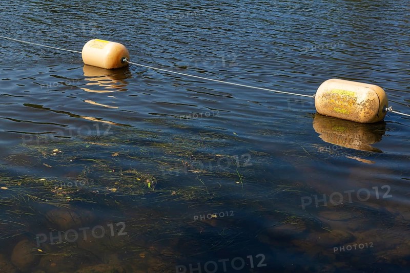 String of yellow cautionary navigation buoys on river water surface serving to warn, signal or indicate of a hazard beyond, Terrebonne, Quebec, Canada