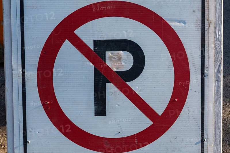 Close-up of posted white, red and black No Parking pictogram notice sign outdoors, Quebec, Canada