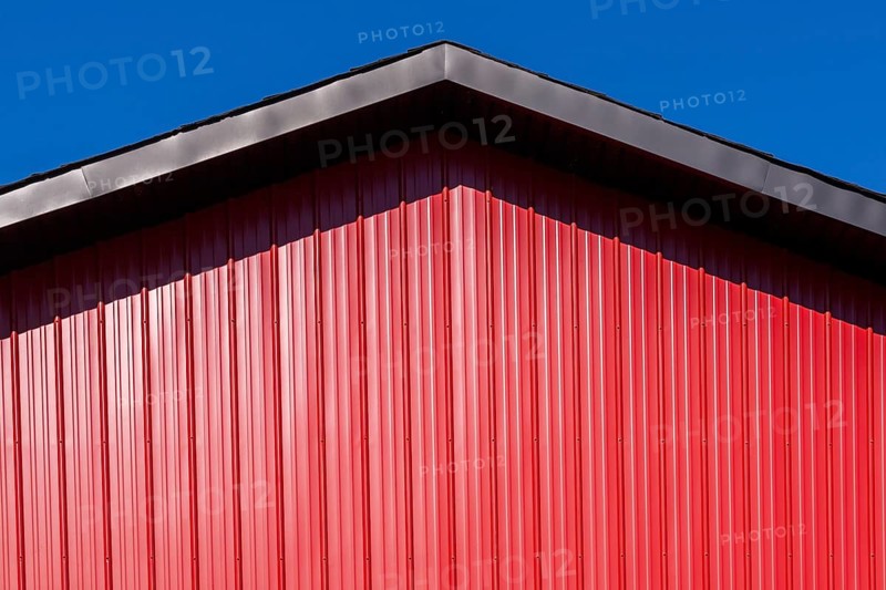 Close-up of building with black metal trim gable roof edge and cladded with red sheet metal siding, Quebec, Canada