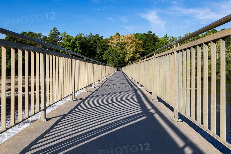 Wide angle view of pedestrian walkway on top of water flow control Moulin Neuf dam over Des Mille-Iles river in summer, Old Terrebonne, Quebec, Canada