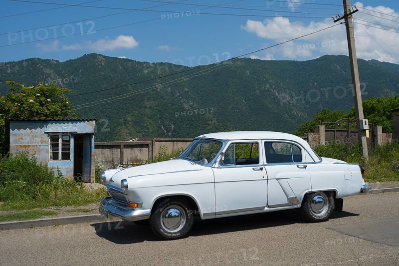 White vintage car on a country road with mountain backdrop and blue sky in summer, GAZ M-21 Volga, Odsun, Odzun, Debed Gorge, Lorikeet Province, Armenia