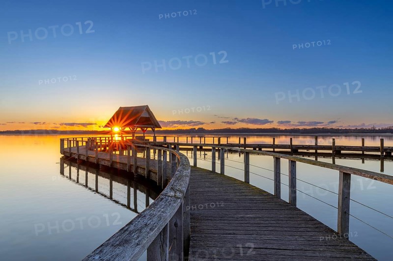 Wooden jetty on Lake Hemmelsdorf / Hemmelsdorfer See at sunrise in spring near Lübeck, Schleswig-Holstein, Germany