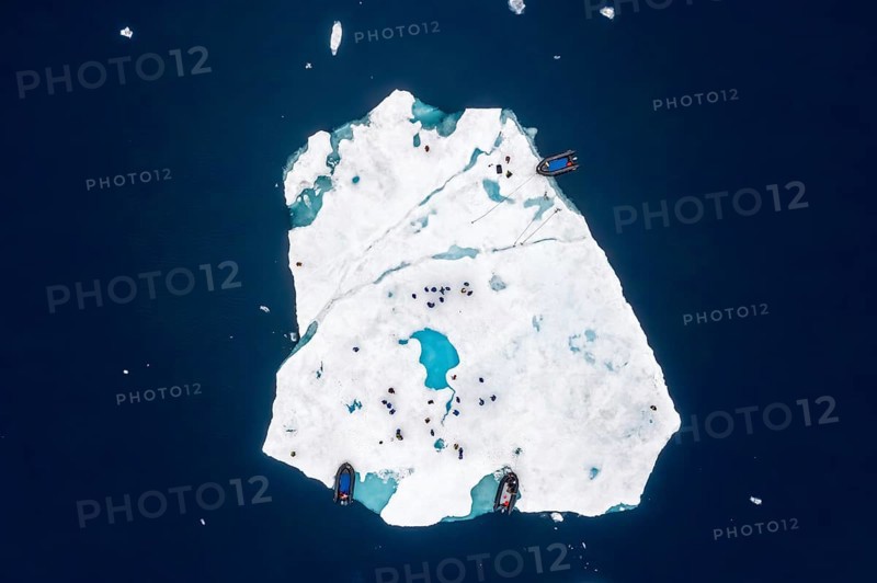 Aerial view over ecotourists from Iceland Pro Cruises walking on ice floe drifting in the Arctic Ocean in summer at Svalbard / Spitsbergen, Norway
