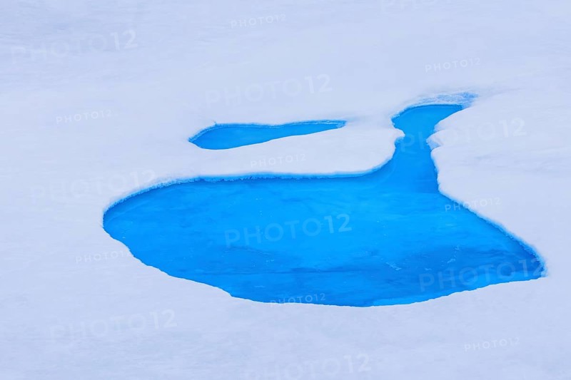 Aerial view over vivid blue water of meltpond / melt pond / meltwater pool on sea ice in the Arctic Ocean at Svalbard / Spitsbergen, Norway