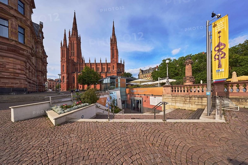 Sam - Stadtmuseum am Markt, entrance, staircase, flower bed, advertising flag on flagpoles, sandstone wall, Protestant market church community Wiesbaden, church market church, neo-Gothic style, architect Carl Boos, square made of paving stones, outdoor area of a restaurant, historic building, trees, blue sky, cumulus clouds, market square, Wiesbaden, state capital, district-free city, Hesse, Germany