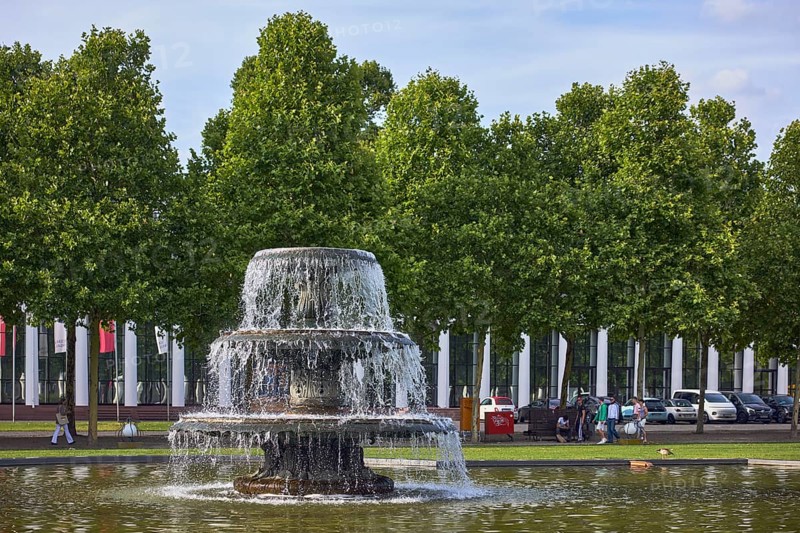 Cascade fountain, lawn, trees, general buildings, pedestrians as accessories, frozen movement, depth of focus with blurred background, milky blue sky, diffuse light, slightly sunny, bowling green, Kurhausplatz, Wiesbaden, state capital, district-free city, Hesse, Germany