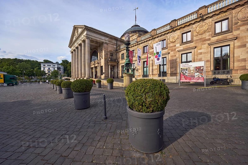 Spa hotel, architectural style neoclassicism, architect Friedrich von Thiersch, building material sandstone, facade with windows, columns, planter with boxwood (Buxus sempervirens), milky blue sky, diffuse light, slightly sunny, evening light, square Kurhausplatz, Wiesbaden, state capital, independent city, Hesse, Germany