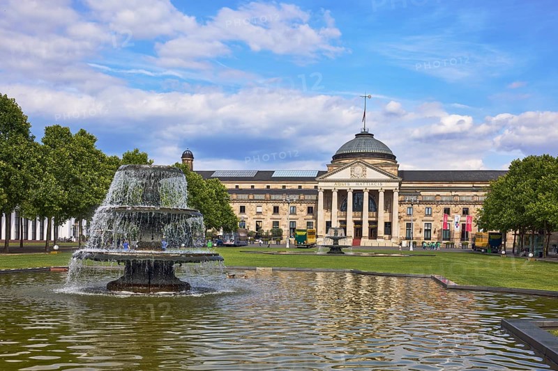 Spa hotel, neo-classical style, architect Friedrich von Thiersch, columns, gardens, trees, lawn, bowling green, abstract reflections on the water surface, blue sky, cumulus clouds, Kurhausplatz square, Wiesbaden, state capital, district-free city, Hesse, Germany