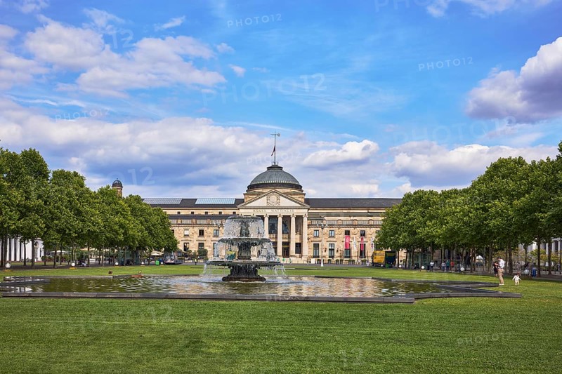 Spa hotel, neo-classical style, architect Friedrich von Thiersch, columns, gardens, bowling green, lawn, trees, cascade fountain, blue sky, cumulus clouds, Kurhausplatz square, Wiesbaden, state capital, district-free city, Hesse, Germany