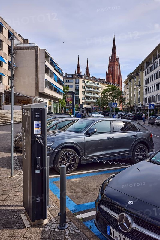 Electric car, charging station for e-cars, charging process, general architecture, residential buildings and commercial buildings, church tower of the market church, cloudy, diffuse light, slightly sunny, street An den Quellen, Wiesbaden, state capital, district-free city, Hesse, Germany
