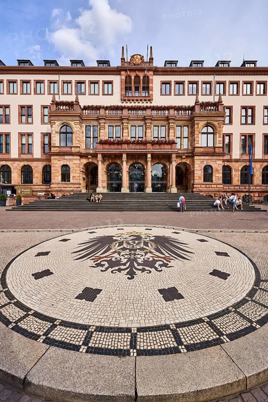 New town hall, historic building, neo-Renaissance style, architect Georg von Hauberrisser, paving stone square, imperial eagle of the German Empire, entrance, staircase, façade with windows, pedestrians as accessories, sitting people, blue sky, cumulus clouds, Schlossplatz square, Wiesbaden, state capital, district-free city, Hesse, Germany