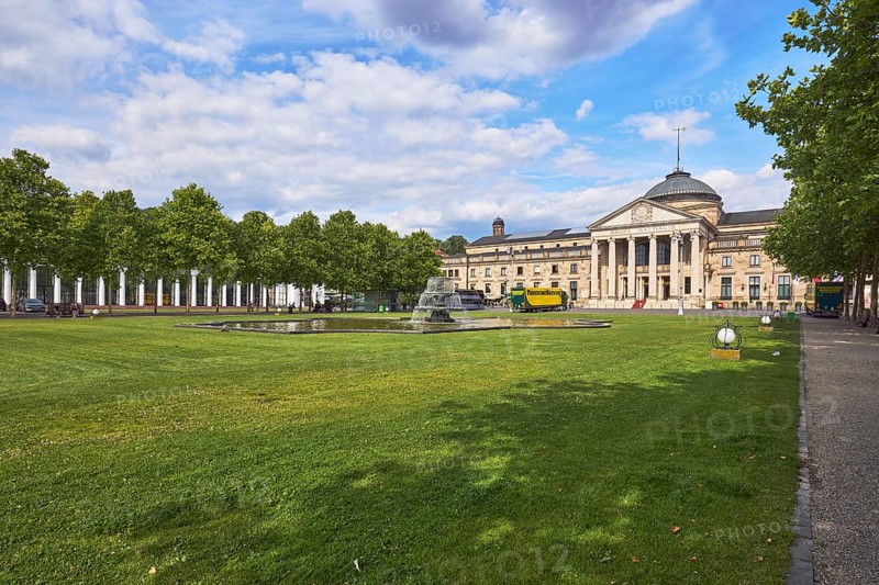 Spa hotel, architectural style neoclassicism, architect Friedrich von Thiersch, columns, green area, trees, Platanus × acerifolia (Platanus ×hispanica), lawn, bowling green, paths, cascading fountain, blue sky, cumulus clouds, Kurhausplatz square, Wiesbaden, state capital, independent city, Hesse, Germany