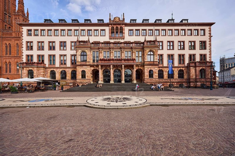 New Town Hall, Historic Building, Neo-Renaissance Style, Architect Georg von Hauberrisser, Entrance Area, Staircase, Facade with Windows, Paving Stone Square, Imperial Eagle of the German Empire Mosaic, Pedestrians as Accessories, Seated People, Blue Sky, Cumulus Clouds, Palace Square, Wiesbaden, State Capital, Independent City, Hesse, Germany