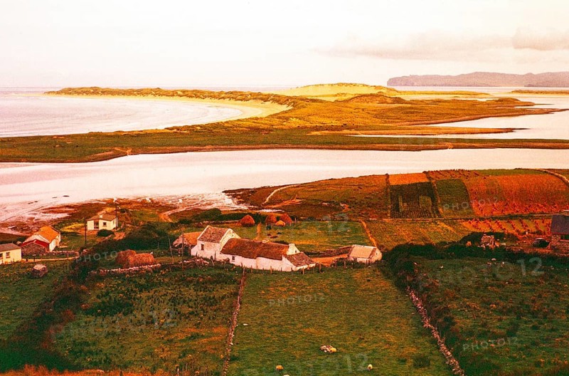 View over thatched farmhouse buildings to Magheraroarty Beach, Meenlaragh, County Donegal, Ireland 1960s
