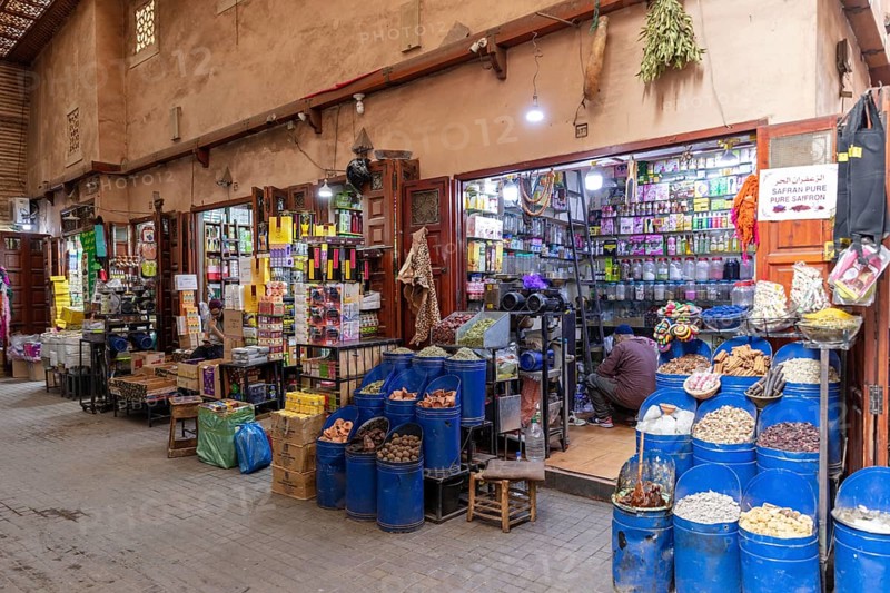 A colorful market stand full of spices, genes and products with a retailer inside a small shop, Marrakech, Medina in Morocco