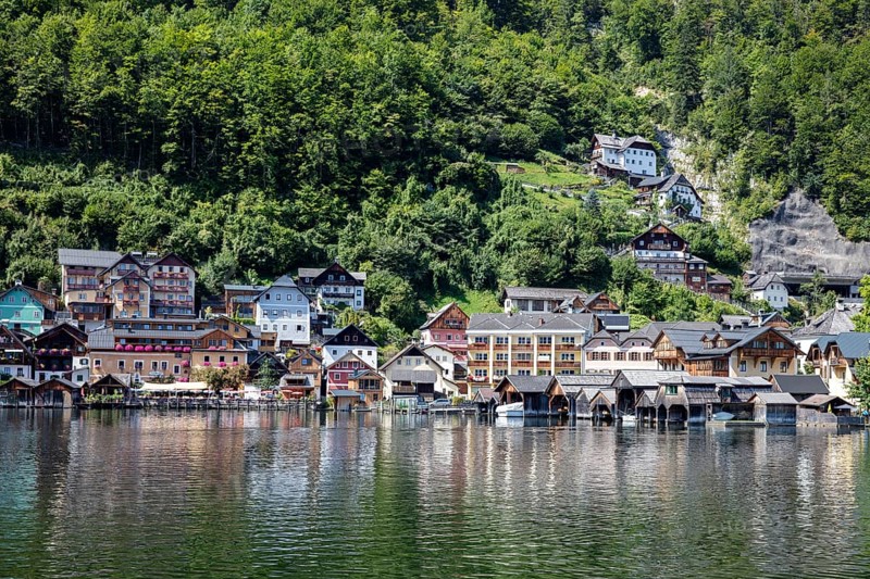 A, Hallstatt, Traditional wooden houses on the shore, surrounded by lush greenery and water, Austria