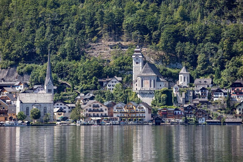 A, Hallstatt, A picturesque village with a lakeside church against a wooded mountain backdrop, Austria