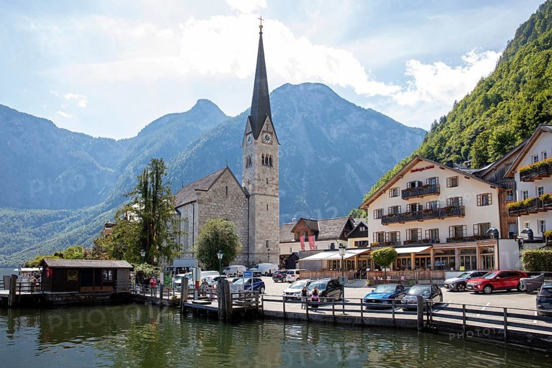 A, Hallstatt, church next to a lake in front of impressive mountains and clouds, quiet scenery, Austria