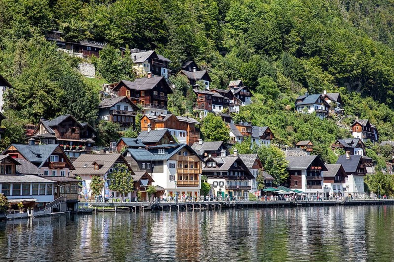 A, Hallstatt, lakeside village with numerous wooden houses, surrounded by lush greenery and peaceful atmosphere, Austria
