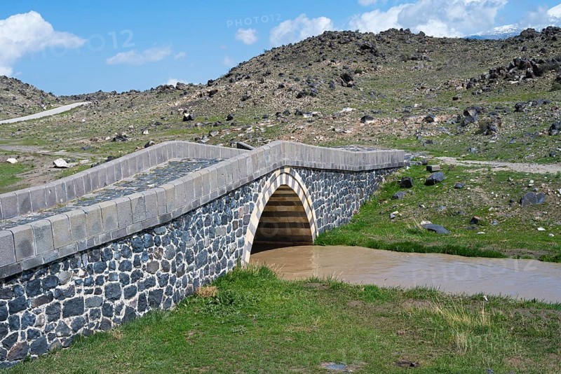 Stone bridge over a small river surrounded by rocky landscape under blue sky, bridge near Cevirme, Dogubayazit, Dogubayazit, Dogubeyazit, Agri Province, Agri, Eastern Anatolia, Anatolia, Turkey