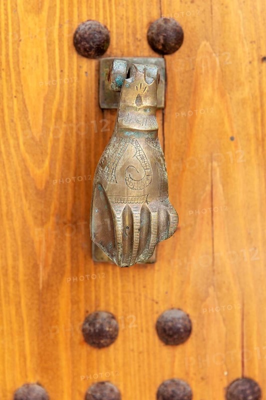 Hand-shaped metal knocker on a wooden door