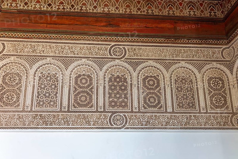 Complex arabesque patterns adorn a wall in a traditional style. Bahia Palace in Marrakech, Morocco