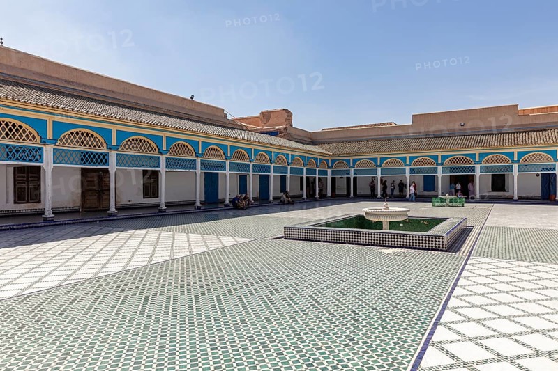Spacious courtyard with central fountain and colorful arcades in the shadow of the sky, Bahia Palace in Marrakech, Morocco