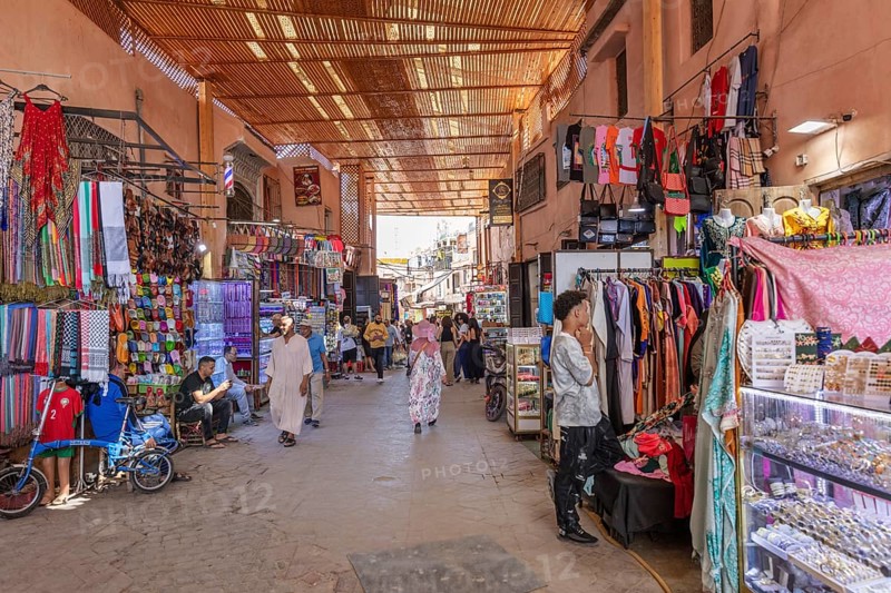 Traditional market hall with people strolling through colorful clothing stores